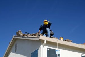 man on top of roof replacing shingles